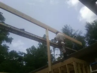 Carpenter setting a ridge beam over a new addition frame — Ice Dam Removal by Roofing Brothers in Junction City