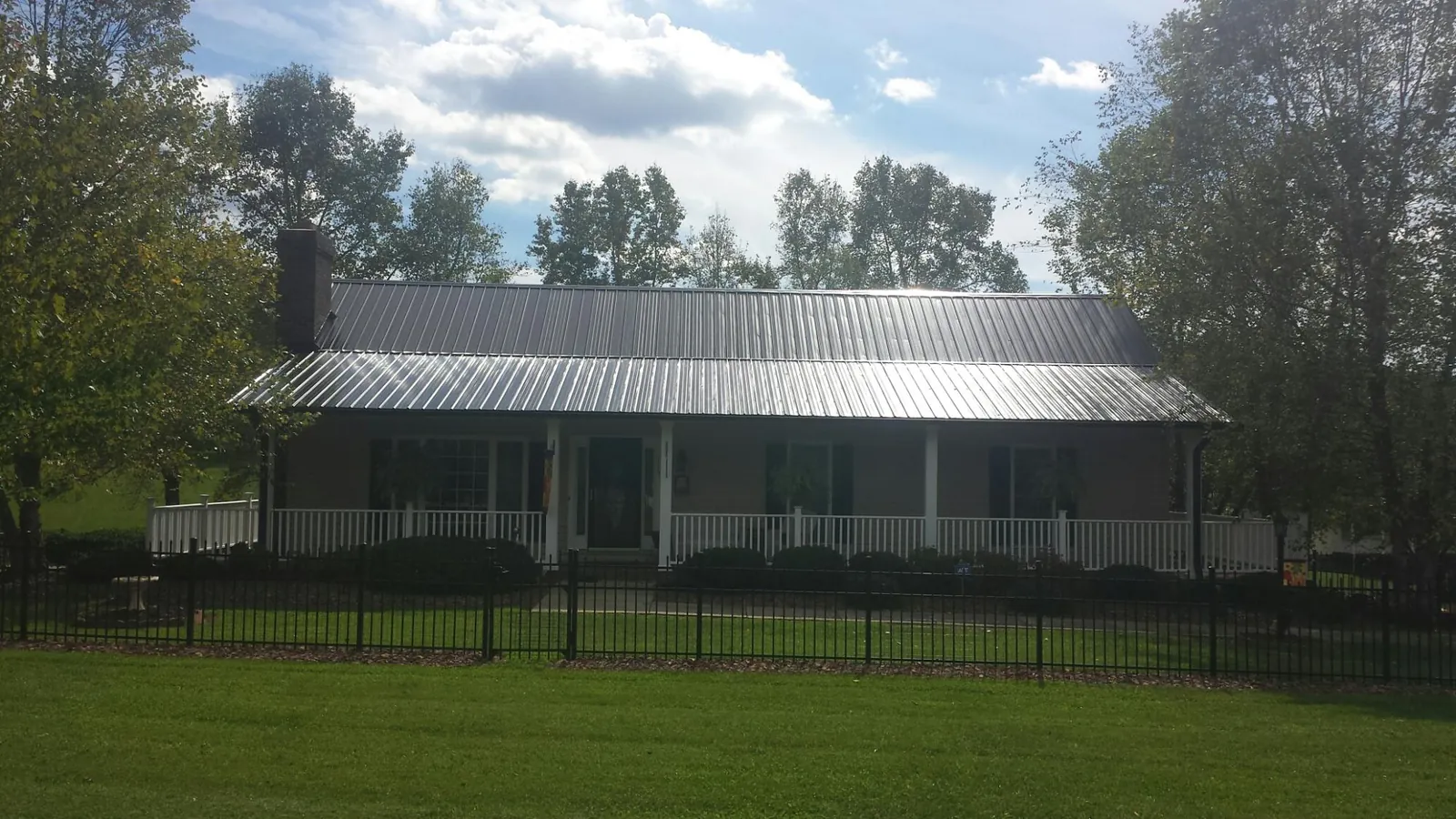 Gray metal roof on a brick ranch with a full width front porch — Gutter Guard Installation work by our crew in Junction City