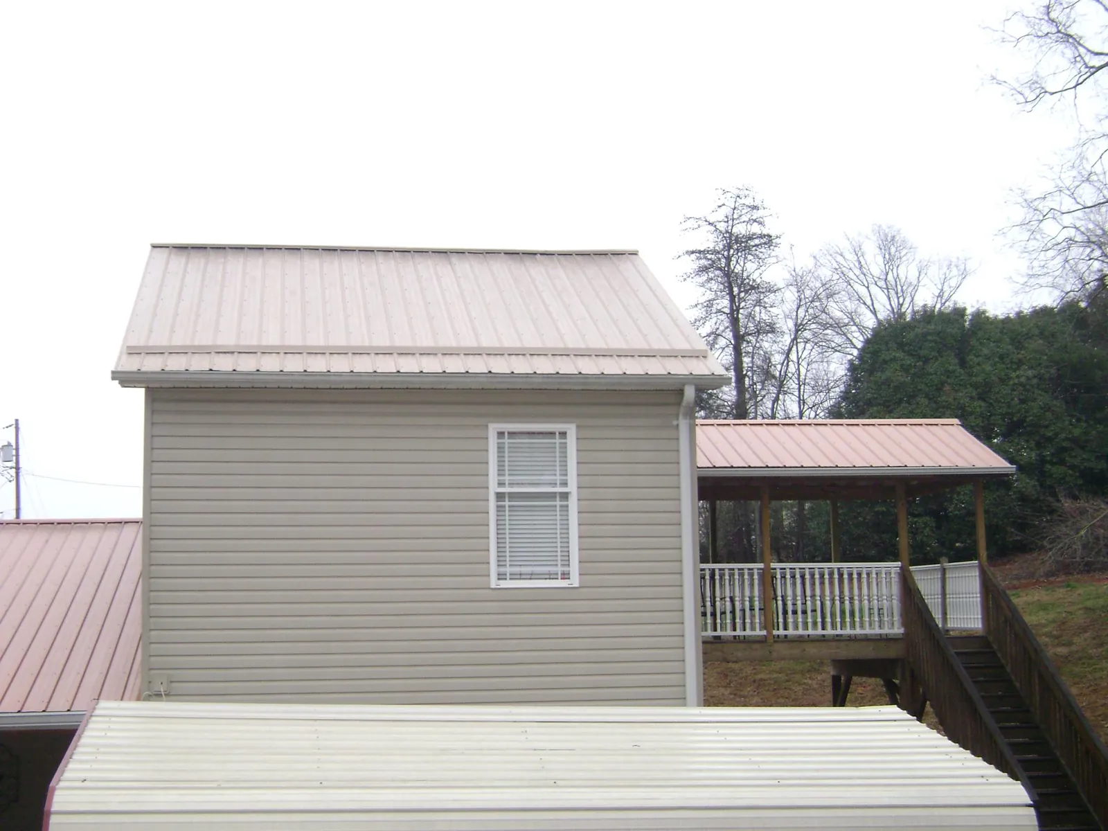 Tan metal roofs on a two story addition and attached porch, from a Roof Replacement job in Junction City